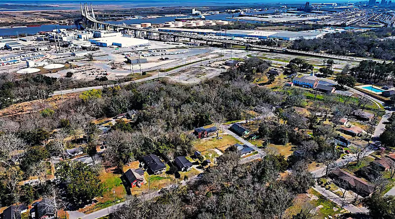 Aerial view of Africatown: homes in the foreground against the bridge, rail lines, and heavy industry
